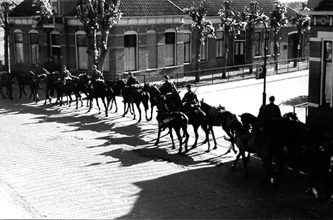 Op 10 mei 1940, vroeg in de morgen, rijden Duitse militairen op hun paarden door de Hoofdstraat in Emmen. De foto is door Piet Meilink gemaakt.