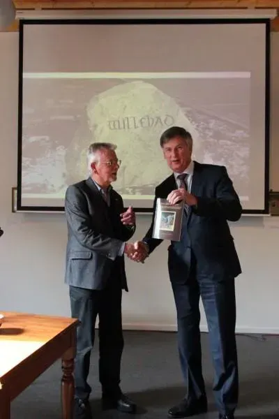 Dirk Otten reikt het eerste exemplaar van zijn boek Willehad uit aan gedeputeerde Cees Bijl.